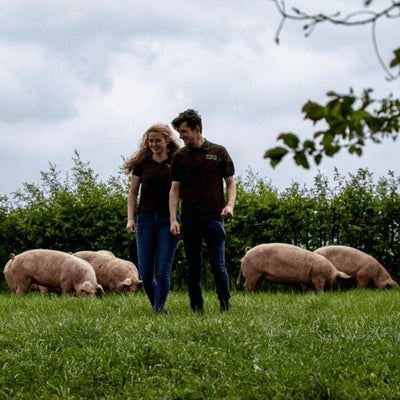 Eigenaren van Kuusj in een wei met varkens
